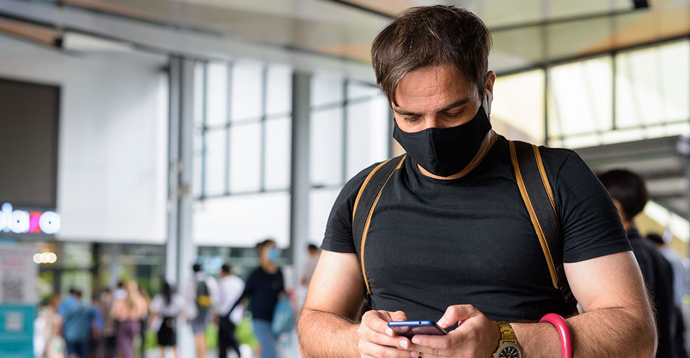 retail shopper in a mall with a face mask using a smartphone